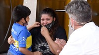 Ada pula seorang anak dengan jersey Boca Junior berusaha menenangkan sang ibu. Boca Junior adalah klub yang pernah dibela Maradona. (Foto: Getty Images/Fotonoticias)