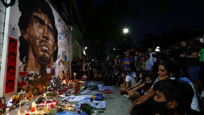 Soccer fans hold a vigil for Diego Maradona outside the stadium of Argentinos Juniors soccer club, where he started as a professional footballer, in Buenos Aires, Argentina, Wednesday, Nov. 25, 2020. The Argentine soccer great who was among the best players ever and who led his country to the 1986 World Cup title died from a heart attack at his home in Buenos Aires. He was 60. (AP Photo/Marcos Brindicci)