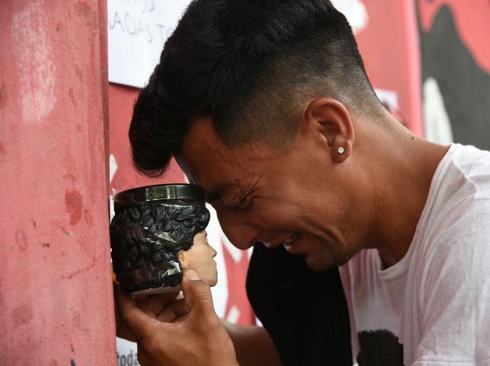 ROSARIO, ARGENTINA - NOVEMBER 25: A fan cries as he holds a replica of Diego Maradona's head at Marcelo Bielsa Stadium after the news of the death of Diego Maradona was known on November 25, 2020 in Rosario, Argentina. Diego Maradona, considered one of the biggest football stars in history, died at 60 from a heart attack on Wednesday in Buenos Aires.  (Photo by Luciano Bisbal/Getty Images)