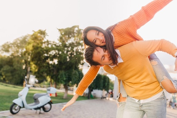 tanned-woman-sweater-funny-posing-with-boyfriend-far-from-scooter_197531-5930