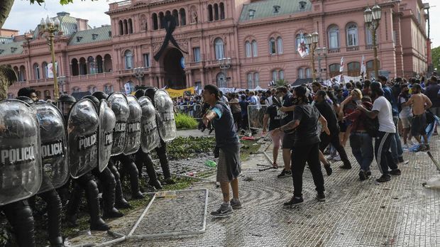Soccer fans waiting to attend the wake for Diego Maradona face off police outside the presidential palace in Buenos Aires, Argentina, Thursday, Nov. 26, 2020. The Argentine soccer great who led his country to the 1986 World Cup title, died Wednesday at the age of 60. (AP Photo/Rodrigo Abd)