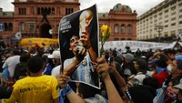 Warga mendatangi halaman istana kepresidenan Argentina dengan membawa beragam atribut dan aksesoris terkait Maradona untuk memberikan penghormatan terakhir bagi sang legenda sepakbola Argentina tersebut. AP Photo/Natacha Pisarenko.