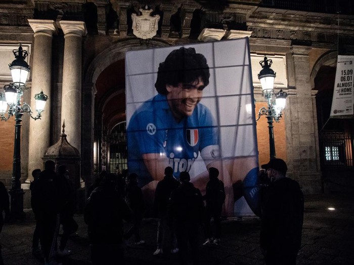NAPLES, ITALY - NOVEMBER 26: A parade of supporters in Piazza del Plebiscito, where a choreography with red smoke bombs was set up to remember Diego Armando Maradona on November 26, 2020 in Naples, Italy. Diego Armando Maradona died at 60 after a cardiocirculatory arrest while he was at his house in Tigre, Argentina, where he was spending his convalescence after brain surgery three weeks before. (Photo by Ivan Romano/Getty Images)