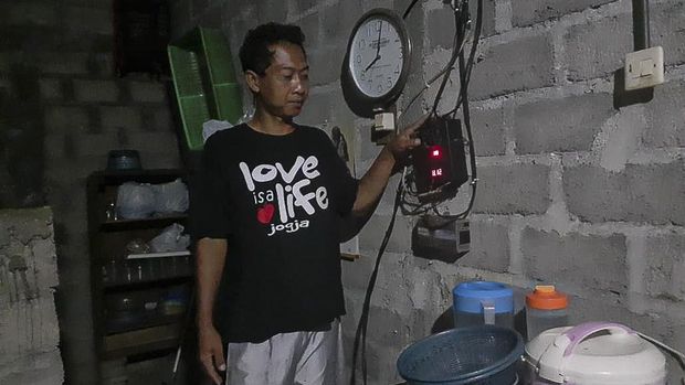 Wartono di depan  screen control untuk memantau besaran daya dan sinar matahari yang diserap panel di atap rumahnya.