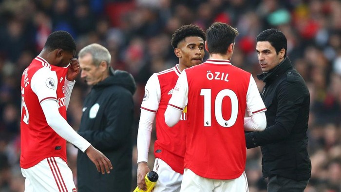 LONDON, ENGLAND - DECEMBER 29: Mikel Arteta, Manager of Arsenal speaks with Mesut Ozil and Reiss Nelson during the Premier League match between Arsenal FC and Chelsea FC at Emirates Stadium on December 29, 2019 in London, United Kingdom. (Photo by Julian Finney/Getty Images)