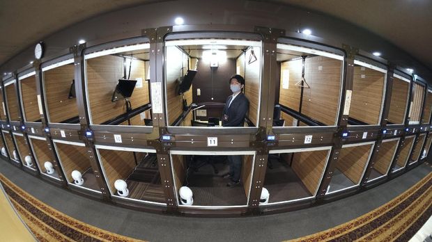 This picture taken with a fisheye lens on November 27, 2020 shows coworking rooms of the capsule hotel Anshin Oyado Shinjuku, Tokyo, which has been renovated into a coworking space without the upper and lower partitions of the capsule. - Facing unprecendented challenges due to the Covid-19 coronavirus pandemic, the capsule hotel renovated an entire floor to be used as a coworking space - offering office necessities such as high speed internet required for telework and web conferencing, including computer hardware and other computing devices. (Photo by Kazuhiro NOGI / AFP)