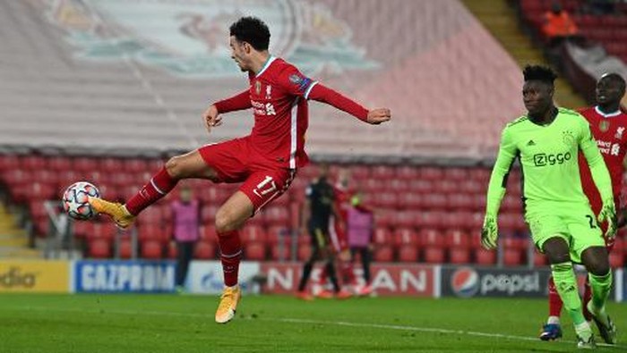 Liverpools English midfielder Curtis Jones (L) scores the opening goal after a mistake from Ajaxs Cameroon goalkeeper Andre Onana (R) during the UEFA Champions League 1st round Group D football match between Liverpool and Ajax at Anfield  in Liverpool, north west England on December 1, 2020. (Photo by Paul ELLIS / POOL / AFP)
