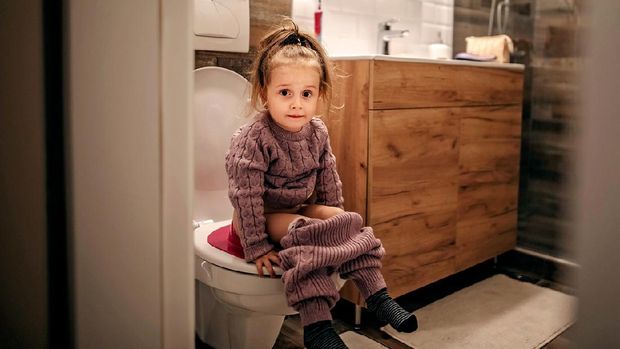 Sad baby boy sitting on chamber pot because he must stop using diapers. Potty training concept