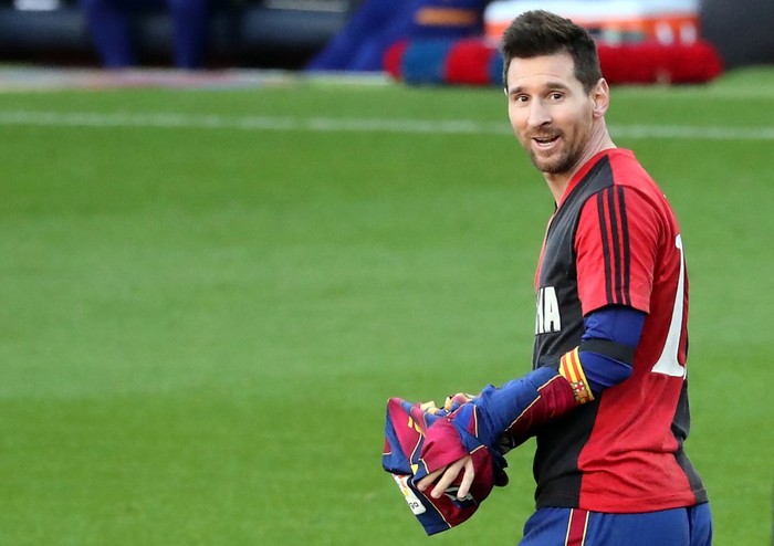 Barcelonas Argentinian forward Lionel Messi puts on his teams jersey after paying tribute for late Argentinian football legend Diego Maradona by revealing a Newells Old Boys jersey after scoring his teams fourth goal during the Spanish League football match between FC Barcelona and CA Osasuna at the Camp Nou stadium in Barcelona, on November 29, 2020. (Photo by J. Bassa / AFP)