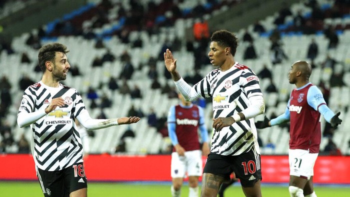 Manchester Uniteds Marcus Rashford, right, celebrates with teammate Manchester Uniteds Bruno Fernandes after scoring his sides third goal during the English Premier League soccer match between West Ham United and Manchester United at the London stadium in London, England, Saturday, Dec. 5, 2020.(Adam Davy / Pool via AP)