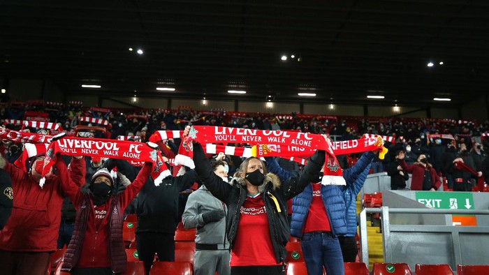LIVERPOOL, ENGLAND - DECEMBER 06: Liverpool fans hold their scarves aloft and show their support as they social distance in the stand during the Premier League match between Liverpool and Wolverhampton Wanderers at Anfield on December 06, 2020 in Liverpool, England. A limited number of fans (2000) are welcomed back to stadiums to watch elite football across England. This was following easing of restrictions on spectators in tiers one and two areas only. (Photo by Clive Brunskill/Getty Images)