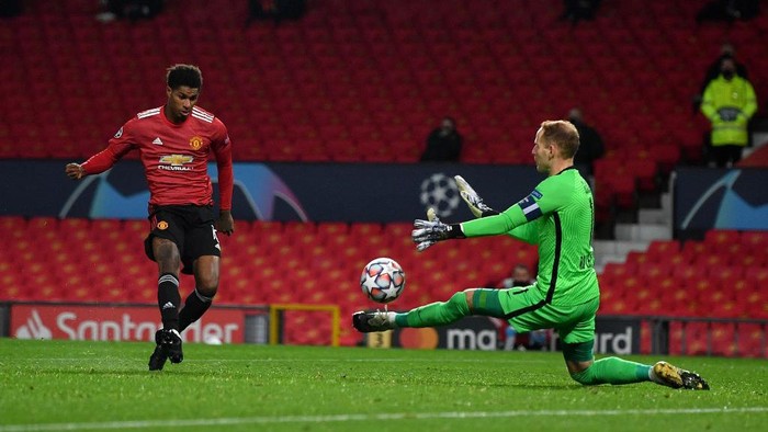 Manchester Uniteds English striker Marcus Rashford (L) scores his teams second goal past RB Leipzigs Hungarian goalkeeper Peter Gulacsi during the UEFA Champions league group H football match between Manchester United and RB Leipzig at Old Trafford stadium in Manchester, north west England, on October 28, 2020. (Photo by Anthony Devlin / AFP)