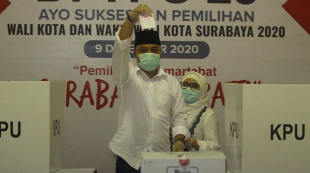 Calon Wali Kota Surabaya nomor urut 01 Eri Cahyadi (kiri) didampingi isterinya Rini Indriyani menunjukkan surat suara saat mencoblos di TPS 25, Ketintang Selatan, Surabaya, Jawa Timur, Rabu (9/12/2020). Pilkada Kota Surabaya 2020 diikuti dua pasangan calon yaitu Eri Cahyadi dan Armuji dengan nomor urut 01 serta pasangan Machfud Arifin dan Mujiaman dengan nomor urut 02. ANTARA FOTO/Moch Asim/wsj.
