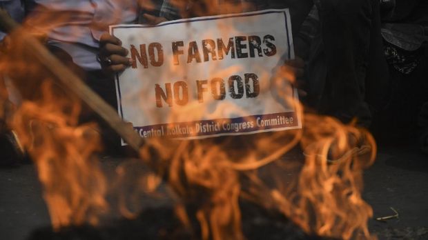 Congress activists hold placards next to a burning an effigy of Prime Minister Narendra Modi while blocking a road during a protest in support of the nationwide general strike called by farmers against the recent agricultural reforms in Kolkata on December 8, 2020. (Photo by Dibyangshu SARKAR / AFP)