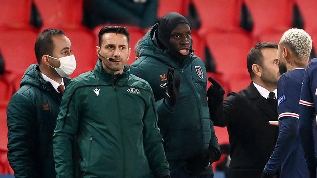 Romanian fourth official Sebastian Coltescu (2nd-L) looks on next to Istanbul Basaksehir's French forward Demba Ba (2nd-R) and Paris Saint-Germain Brazilian forward Neymar (1st-R) during the UEFA Champions League group H football match between Paris Saint-Germain (PSG) and Istanbul Basaksehir FK at the Parc des Princes stadium in Paris, on December 8, 2020. - Paris Saint-Germain's decisive Champions League game with Istanbul Basaksehir was suspended on December 9 in the first half as the players walked off amid allegations of racism by one of the match officials.The row erupted after Basaksehir assistant coach Pierre Webo, the former Cameroon international, was shown a red card during a fierce row on the touchline with staff from the Turkish club appearing to accuse the Romanian fourth official of using a racist term. (Photo by FRANCK FIFE / AFP)
