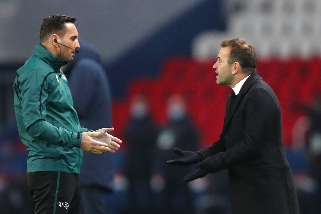 Basaksehir's manager Okan Buruk, right, reacts next to Romanian 4th referee Sebastian Coltescu during the Champions League group H soccer match between Paris Saint Germain and Istanbul Basaksehir at the Parc des Princes stadium in Paris, Tuesday Dec. 8 , 2020. (AP Photo/Francois Mori)