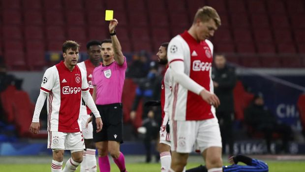 Referee Carlos del Cerro Grande shows a yellow card to Ajax's Nicolas Tagliafico during the group D Champions League soccer match between Ajax and Atalanta at the Johan Cruyff ArenA in Amsterdam, Netherlands, Wednesday, Dec. 9, 2020. (AP Photo/Peter Dejong)