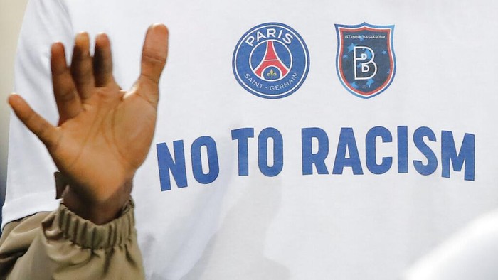 A No To Racism logo on the shirt of Basaksehir assistant coach Pierre Webo prior to the Champions League group H soccer match between Paris Saint Germain and Istanbul Basaksehir at the Parc des Princes stadium in Paris, France, Wednesday, Dec. 9, 2020. The match is resuming on Wednesday with a new refereeing team after players from Paris Saint-Germain and Istanbul Basaksehir left the field on Tuesday evening and didnt return when the fourth official — Sebastian Coltescu of Romania — was accused of using a racial term to identify Basaksehir assistant coach Pierre Webo before sending him off for his conduct on the sidelines. (AP Photo/Francois Mori)