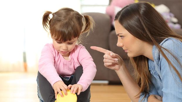 Portrait of a mother scolding to her baby daughter sitting on the floor in the living room at home