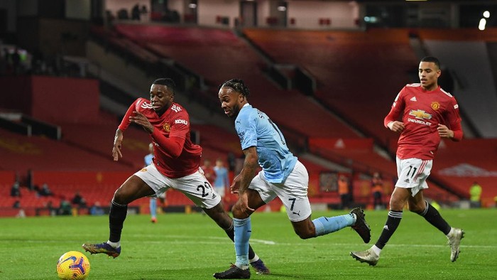 MANCHESTER, ENGLAND - DECEMBER 12: Raheem Sterling of Manchester City  runs with the ball at Aaron Wan-Bissaka of Manchester United as Mason Greenwood looks on during the Premier League match between Manchester United and Manchester City at Old Trafford on December 12, 2020 in Manchester, England. The match will be played without fans, behind closed doors as a Covid-19 precaution. (Photo by Michael Regan/Getty Images)