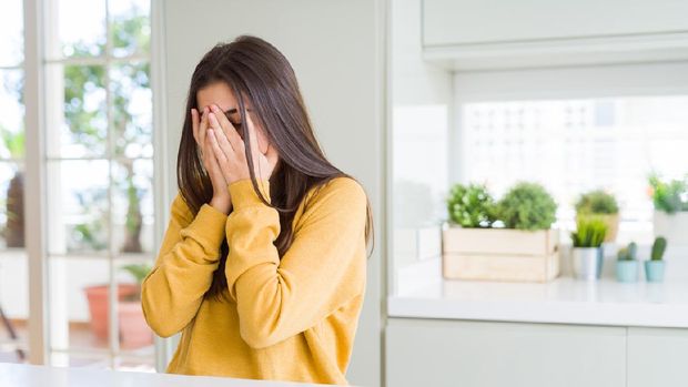 Beautiful young woman wearing yellow sweater with sad expression covering face with hands while crying. Depression concept.