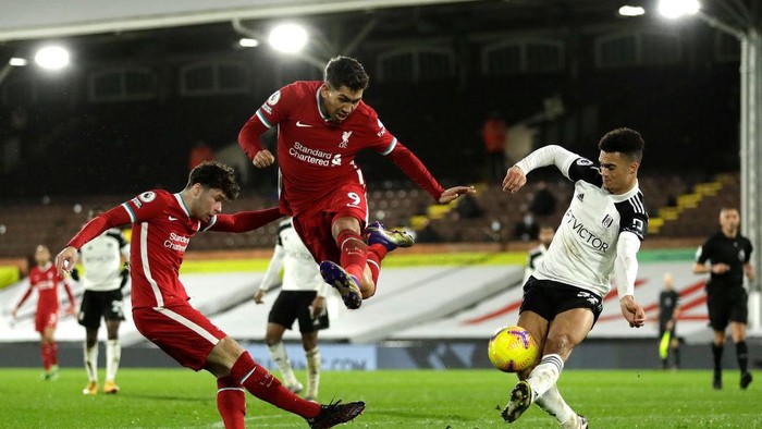 LONDON, ENGLAND - DECEMBER 13: Roberto Firmino of Liverpool jumps out the way as his teammate Neco Williams shoots under pressure from Antonee Robinson of Fulham during the Premier League match between Fulham and Liverpool at Craven Cottage on December 13, 2020 in London, England. A limited number of spectators (2000) are welcomed back to stadiums to watch elite football across England. This was following easing of restrictions on spectators in tiers one and two areas only. (Photo by Matt Dunham - Pool/Getty Images)