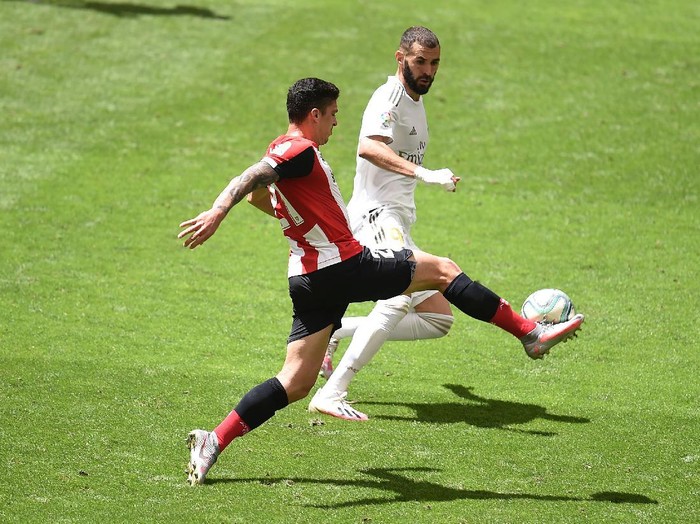 BILBAO, SPAIN - JULY 05: Ander Capa of Athletic Bilbao battles for possession with Karim Benzema of Real Madrid during the La Liga match between Athletic Club and Real Madrid CF at San Mames Stadium on July 05, 2020 in Bilbao, Spain. Football Stadiums around Europe remain empty due to the Coronavirus Pandemic as Government social distancing laws prohibit fans inside venues resulting in all fixtures being played behind closed doors. (Photo by Juan Manuel Serrano Arce/Getty Images)