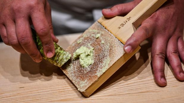 In this picture taken on December 1, 2020, Japanese sushi master Toshiya Matsushita shreds fresh wasabi at his restaurant in Tokyo. - If you've eaten sushi, you might assume you've tried wasabi. But chances are it was an artificial version that Japanese growers say is a world away from their 'green gold'. (Photo by Charly TRIBALLEAU / AFP) / To go with AFP story Japan-food-agriculture-economy-health-virus, FOCUS by Mathias CENA
