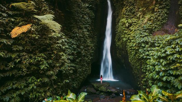 Air Terjun Leke Leke Waterfall in tropical jungle and alone woman in bikini. Leke Leke waterfall in Bali, Indonesia