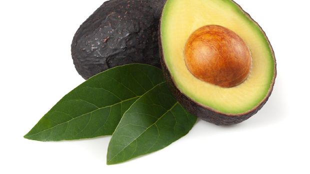 Avocado cut in half, with leaves, on white background