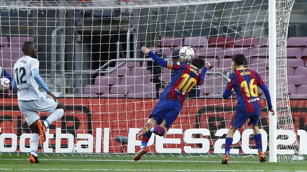 Barcelona's Lionel Messi, centre, heads the ball to score his side 1st goal of the game during the Spanish La Liga soccer match between Barcelona and Valencia at the Camp Nou stadium in Barcelona, Spain, Saturday, Dec. 19, 2020. (AP Photo/Joan Monfort)