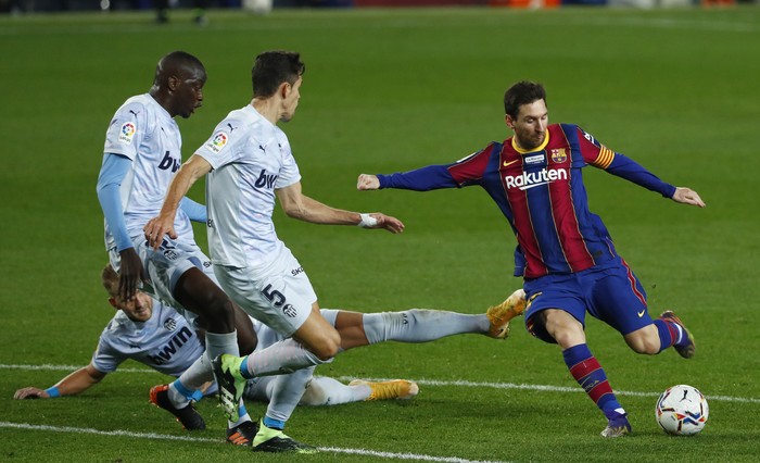 Barcelona's Lionel Messi, right, takes a shot at goal during the Spanish La Liga soccer match between Barcelona and Valencia at the Camp Nou stadium in Barcelona, Spain, Saturday, Dec. 19, 2020. (AP Photo/Joan Monfort)