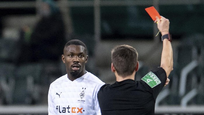 Referee Frank Willenborg shows Moenchengladbachs Marcus Thuram the red card during their German Bundesliga soccer match between Borussia Moenchengladbach and 1899 Hoffenheim at Borussia-Park in Moenchengladbach, Germany, Saturday, Dec. 19, 2020. (Marius Becker/dpa via AP)