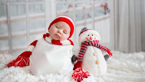 Christmas portrait of cute little newborn baby boy, wearing santa hat and  little cute snowman toy, studio shot, winter time