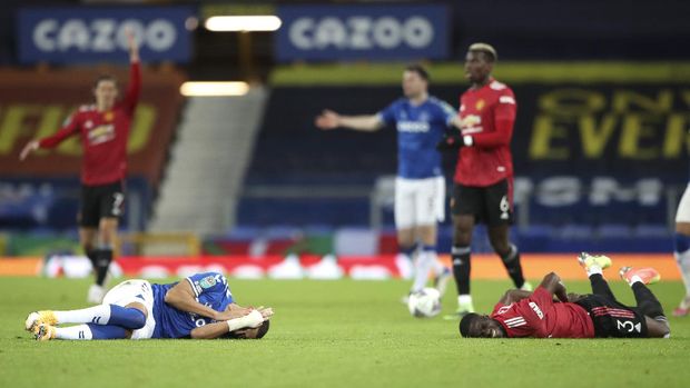 Everton's Richarlison, left, and Manchester United's Eric Bailly react after a collision during the English League Cup quarterfinal soccer match between Everton and Manchester United at Goodison Park, Liverpool, England, Wednesday, Dec. 23, 2020. (AP Photo/Nick Potts,Pool)