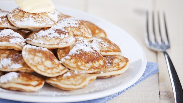 Kue Poffertjes 'Poffertjes': little Dutch pancakes with butter and powdered sugar. Shallow depth of field, focus on lump of butter.