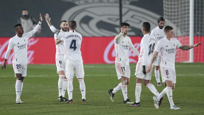 Madrid players Vinicius Junior, left, and Sergio Ramos, third left, celebrate with Karim Benzema, second left, who scored his sides second goal in extra time during the Spanish La Liga soccer match between Real Madrid and Granada at the Alfredo Di Stefano stadium in Madrid, Spain, Wednesday, Dec. 23, 2020. (AP Photo/Bernat Armangue)