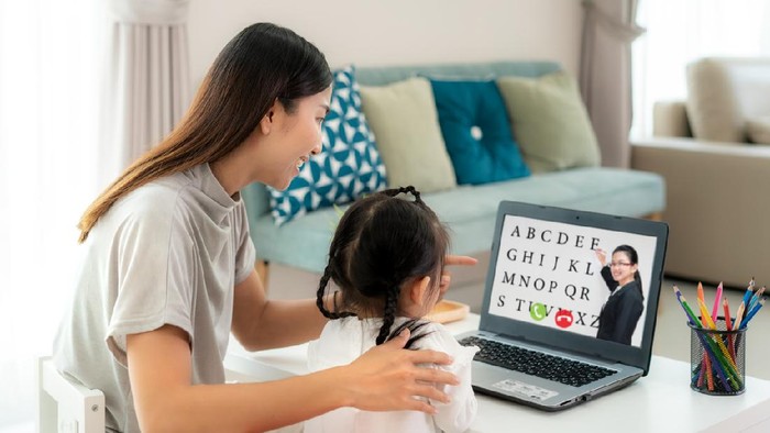 Ilustrasi anak main laptop atau internet Asian kindergarten school girl with mother video conference e-learning with teacher on laptop in living room at home. Homeschooling and distance learning ,online ,education and internet.