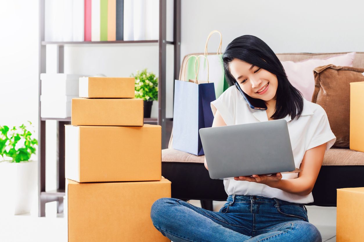 Asian beautiful woman working with laptop and smartphone to online business shop at home.Owner businesswoman start up with Accept orders,Check the products, Prepare to deliver products to customers.