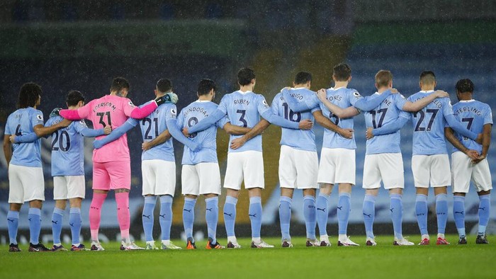 Manchester Citys players stand for a minute of silence in memory of those who have died in 2020 before the English Premier League soccer match between Manchester City and Newcastle United at the Etihad Stadium in Manchester, England, Saturday, Dec., 26, 2020. (Clive Brunskill/Pool via AP)