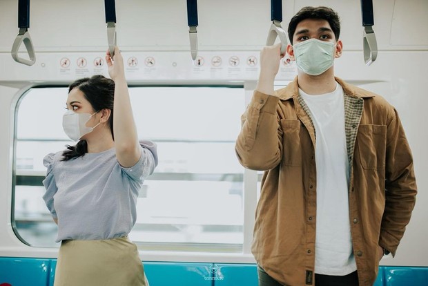 Nabila dan Harits berfoto di dalam rangkaian kereta MRT dan stasiun MRT. Keduanya mengikuti protol kesehatan, yakni mengenakan masker.