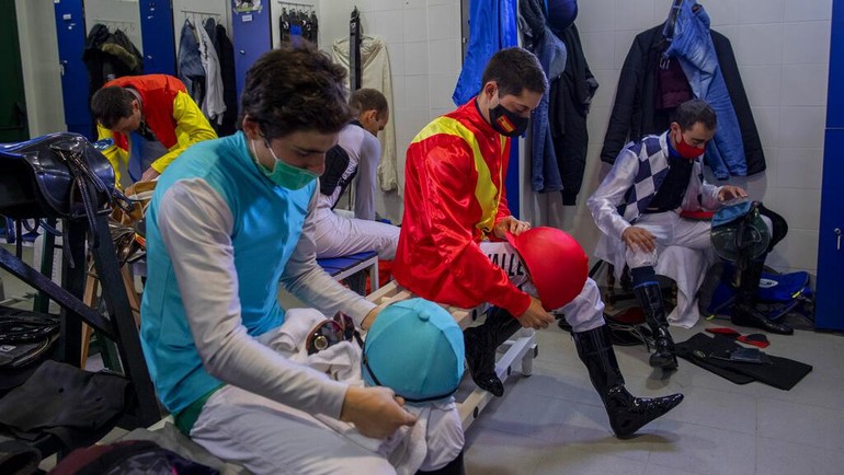 Para joki bersiap di ruang pakaian sebelum berkompetisi di pacuan kuda rumput di Hipodromo de la Zarzuela di Madrid, Spanyol, Minggu, 6 Desember 2020.  
