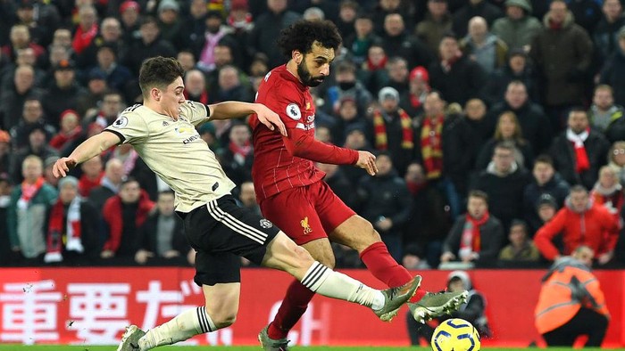 LIVERPOOL, ENGLAND - JANUARY 19: Mohamed Salah of Liverpool scores his teams second goal past David De Gea (not pictured) of Manchester United as he is challenged by Daniel James of Manchester United during the Premier League match between Liverpool FC and Manchester United at Anfield on January 19, 2020 in Liverpool, United Kingdom. (Photo by Michael Regan/Getty Images)