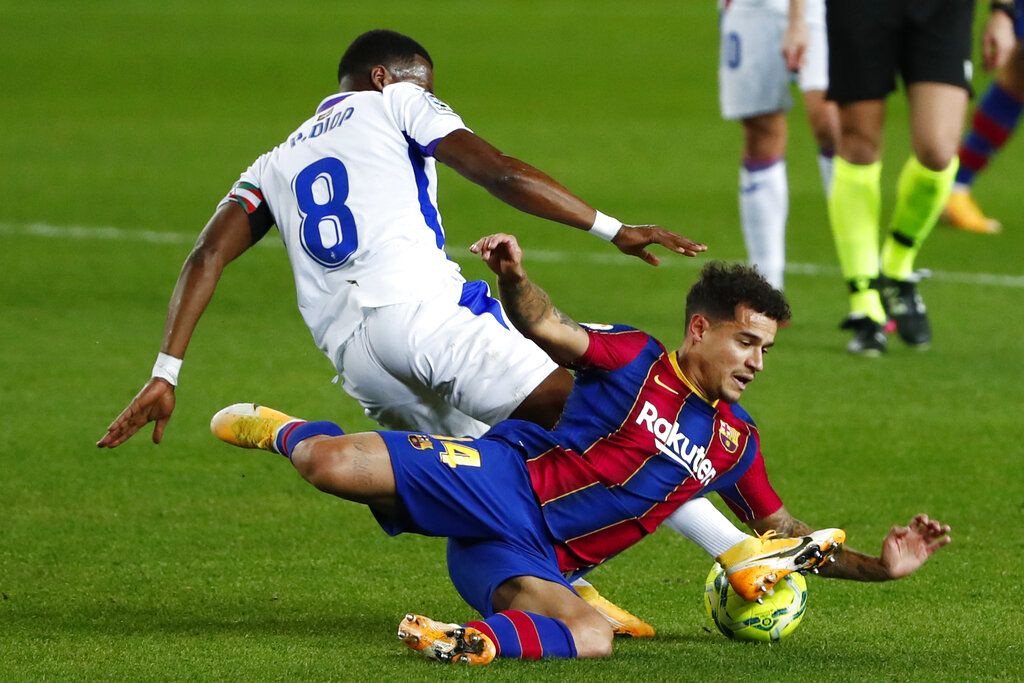 Eibar's Pape Diop, left, challenges Barcelona's Philippe Coutinho during the Spanish La Liga soccer match between Barcelona and Eibar at the Camp Nou stadium in Barcelona in Barcelona, Spain, Tuesday, Dec. 29, 2020. (AP Photo/Joan Monfort)