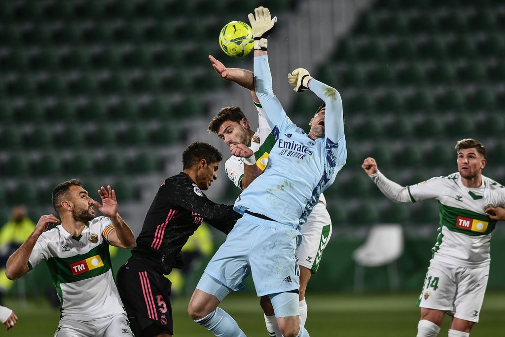 Real Madrid's goalkeeper Thibaut Courtois and Elche's Lucas Boye, center, jump for the ball during the Spanish La Liga soccer match between Real Madrid and Elche CF at the Manuel Martinez Valero stadium in Elche, Spain, Wednesday, Dec. 30, 2020. (AP Photo/Jose Breton)