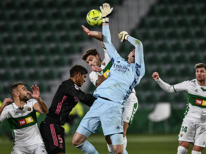 Real Madrid's goalkeeper Thibaut Courtois and Elche's Lucas Boye, center, jump for the ball during the Spanish La Liga soccer match between Real Madrid and Elche CF at the Manuel Martinez Valero stadium in Elche, Spain, Wednesday, Dec. 30, 2020. (AP Photo/Jose Breton)