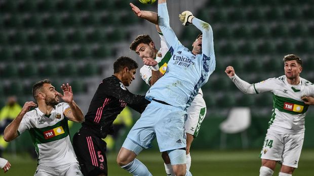 Real Madrid's goalkeeper Thibaut Courtois and Elche's Lucas Boye, center, jump for the ball during the Spanish La Liga soccer match between Real Madrid and Elche CF at the Manuel Martinez Valero stadium in Elche, Spain, Wednesday, Dec. 30, 2020. (AP Photo/Jose Breton)