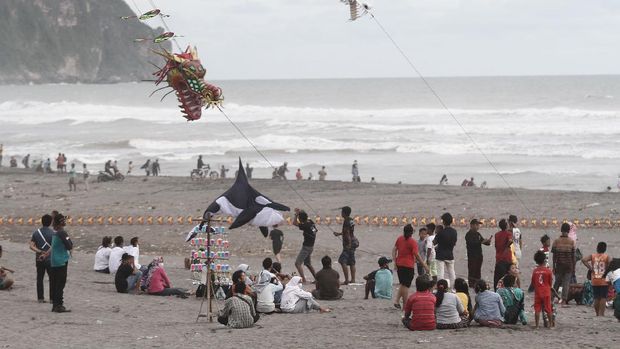 Wisatawan mengunjungi objek wisata Pantai Parangkusumo di Bantul, DI Yogyakarta, Jumat (1/1/2021). Pascapenutupan kawasan wisata pantai selatan Yogyakarta pada malam pergantian tahun baru, pengunjung memadati kawasan tersebut untuk menghabiskan libur tahun baru meskipun kasus COVID-19 di Yogyakarta terus meningkat. ANTARA FOTO/Hendra Nurdiyansyah/aww.