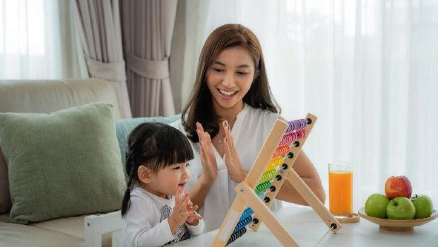 Happy Asian young mother and daughter playing with abacus, early education at home.