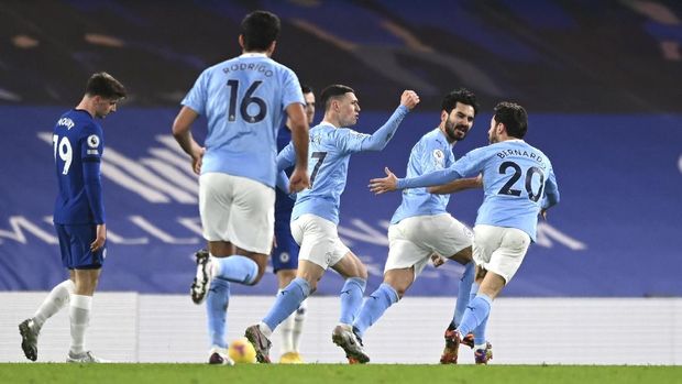 Manchester City's Ilkay Gundogan, second right, celebrates after scoring the opening goal with Manchester City's Bernardo Silva, right, and Manchester City' Phil Foden, centre, during the English Premier League soccer match between Chelsea and Manchester City at Stamford Bridge, London, England, Sunday, Jan. 3, 2021. (Shaun Botterill/Pool via AP)